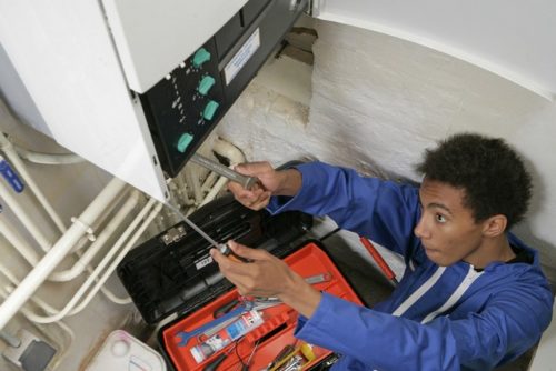 Central heating technician making repairs to a boiler, which is included in central heating services